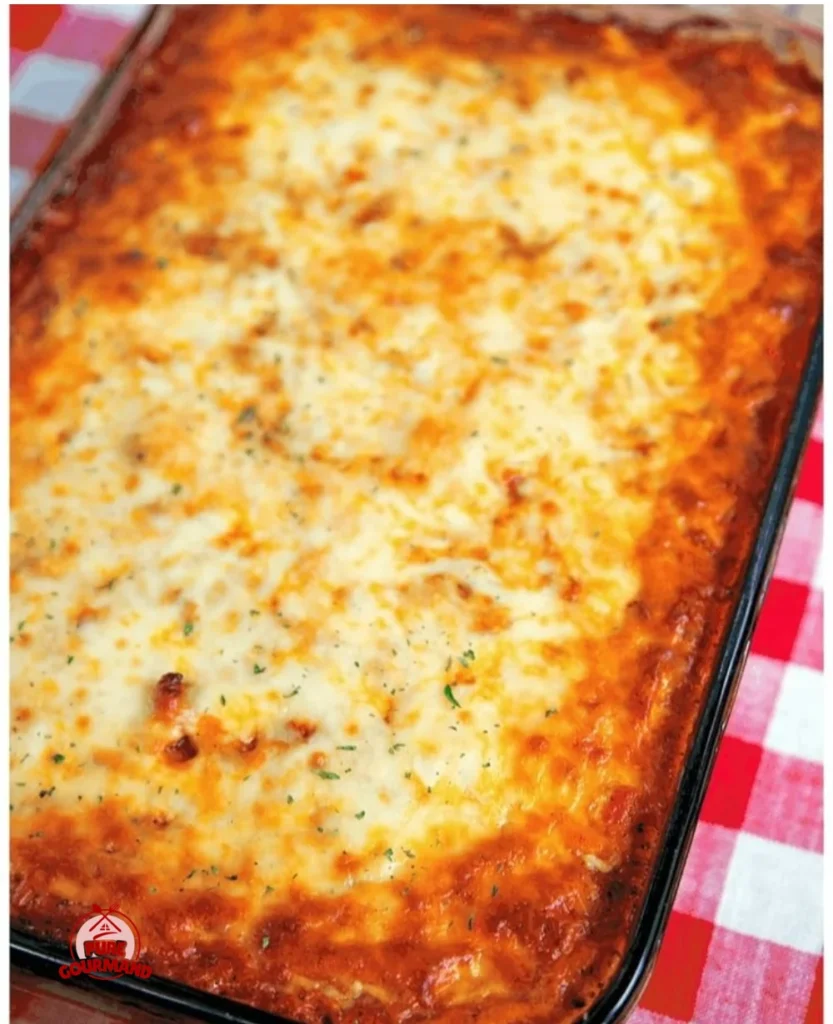 Delicious baked spaghetti topped with cheese and herbs in a casserole dish.