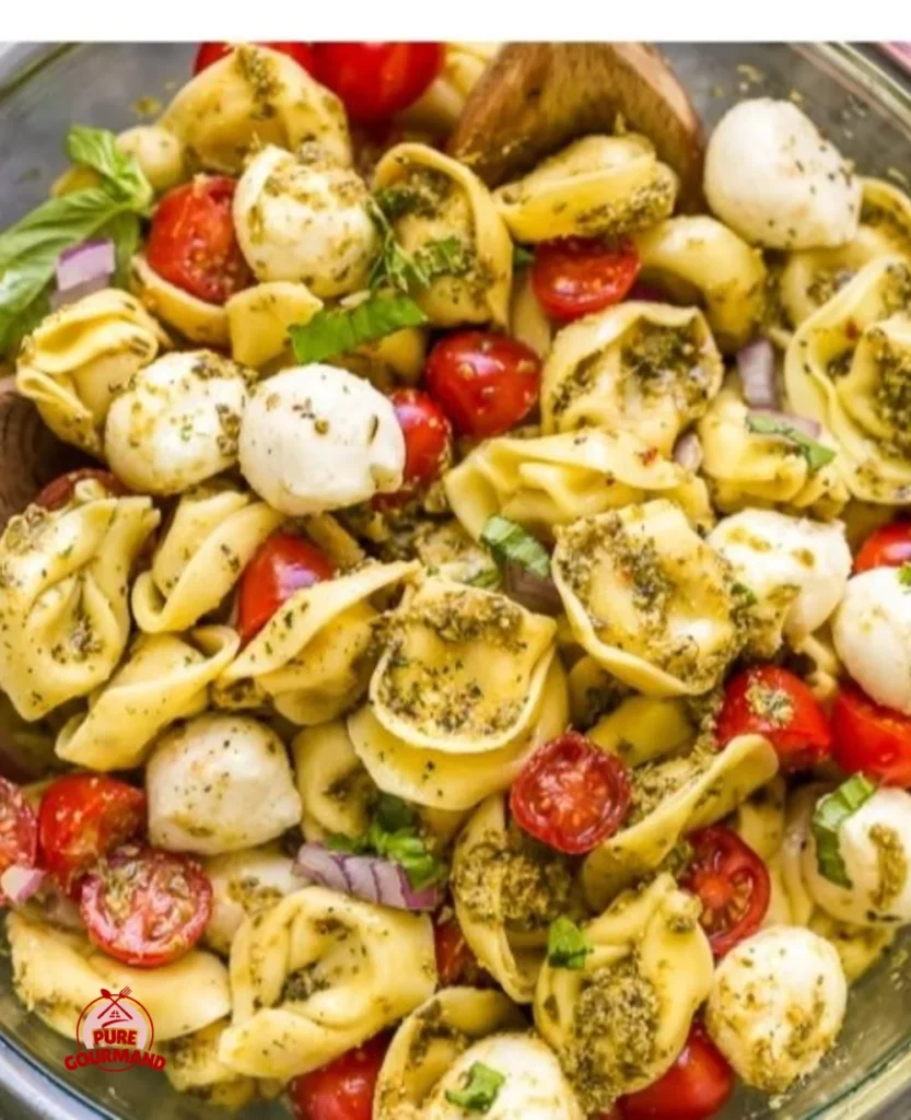 Pesto Tortellini Salad garnished with fresh basil and cherry tomatoes