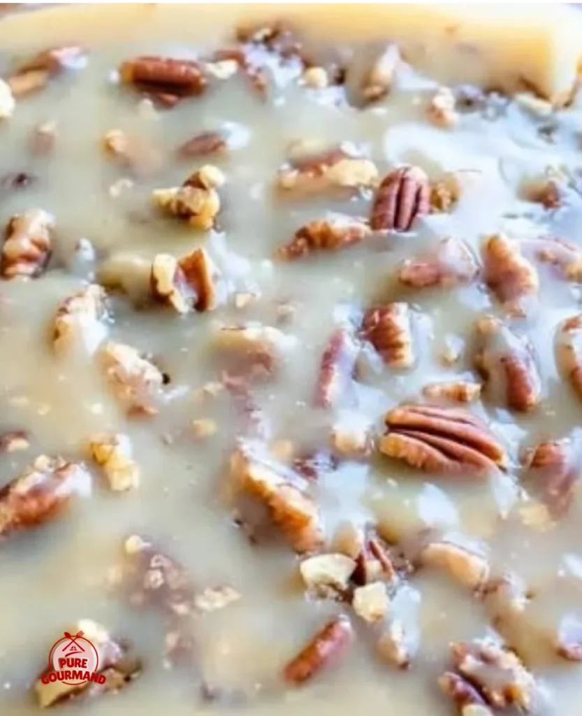 Delicious Butter Pecan Praline Poke Cake topped with pecans and praline sauce.