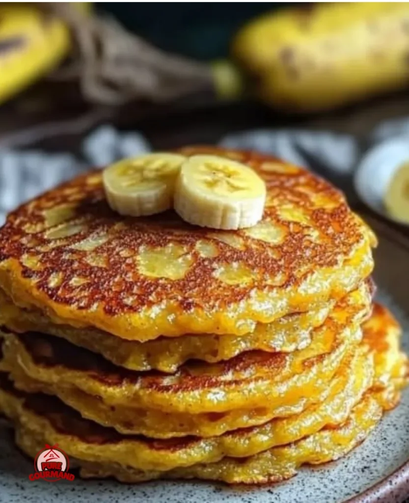 Fluffy plantain pancakes served on a plate with fresh fruit and syrup.