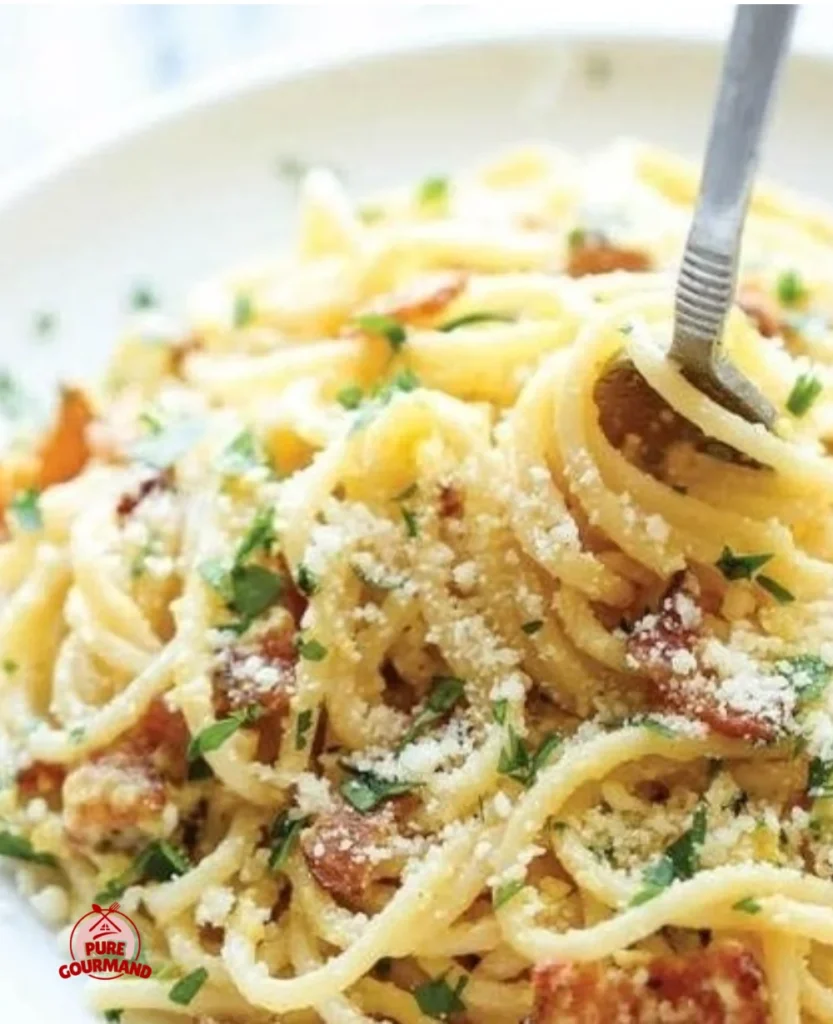 A steaming plate of Spaghetti Carbonara garnished with cheese and pepper.