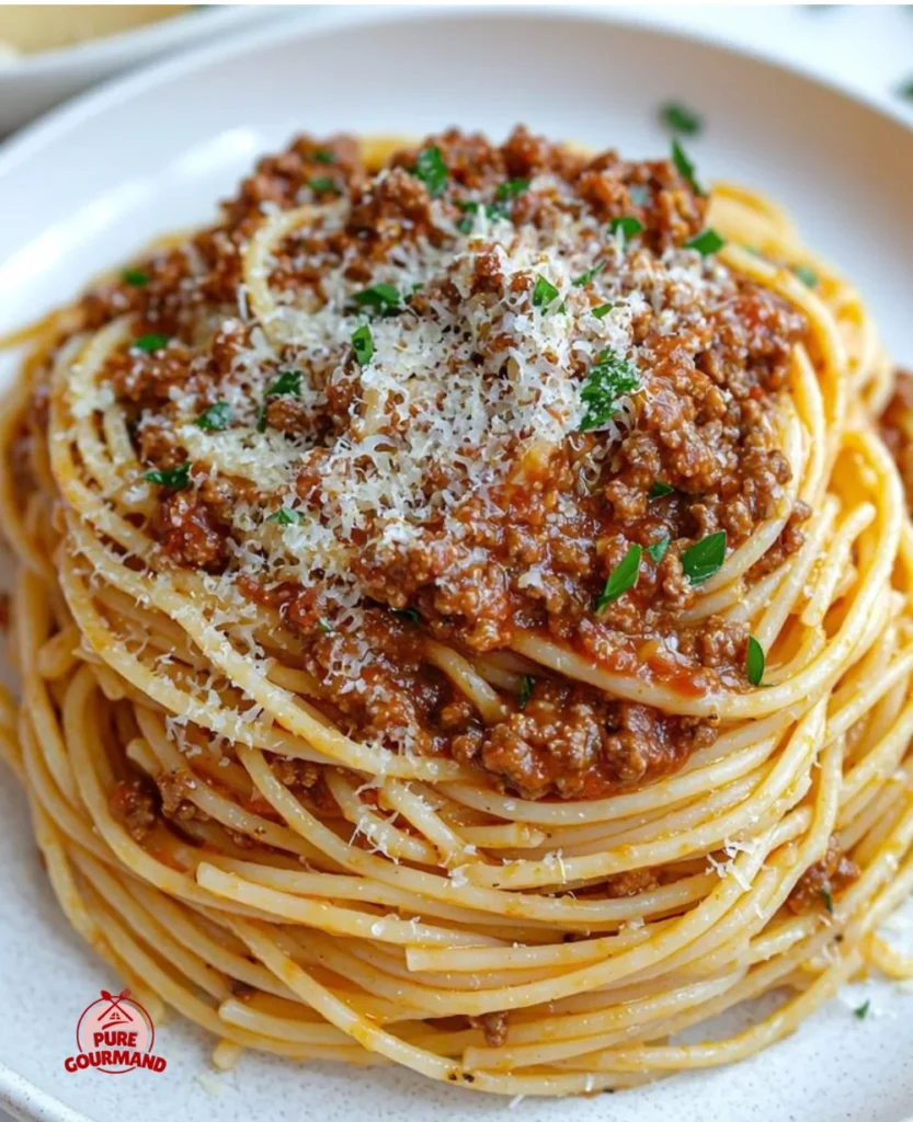 Bowl of spaghetti with meat sauce, garnished with parsley and parmesan cheese.