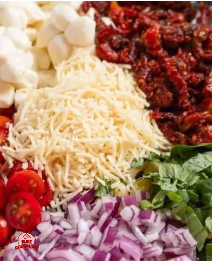 Delicious dried tomato pasta salad served in a bowl with greens and herbs.