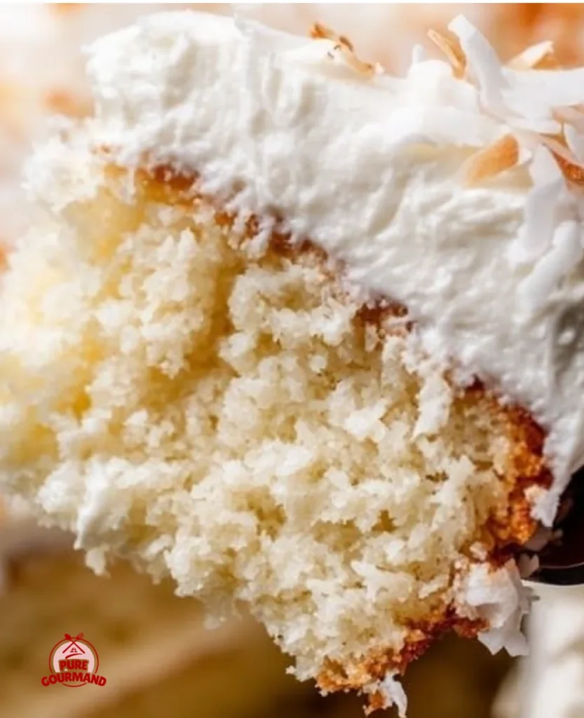 Moist coconut cake made with real coconut milk, garnished with coconut flakes.