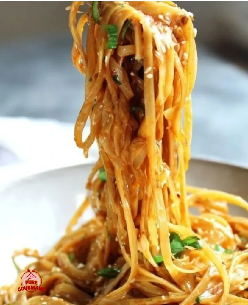Bowl of flavorful peanut noodles topped with fresh vegetables